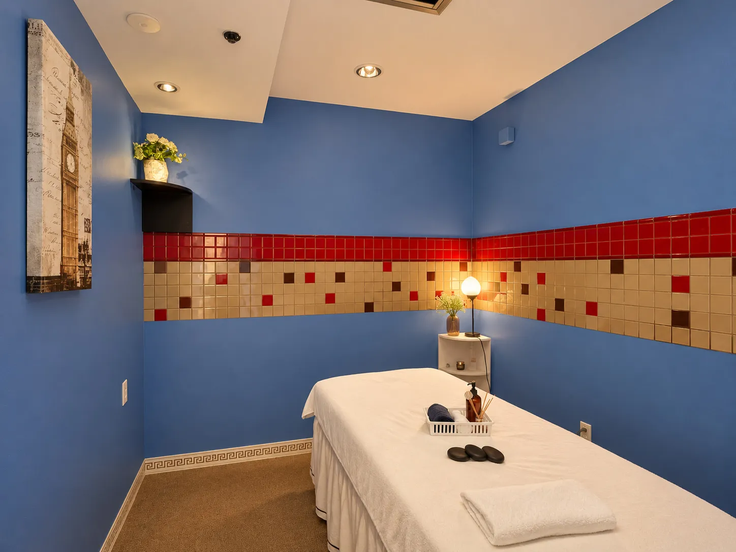 Treatment room at Wellness Massage Spa with blue walls, a tiled border and a massage table made up in white linens